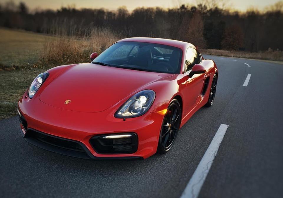Red Porsche Cayman GTS on a country road at dusk